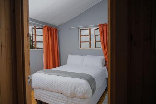 - une chambre avec un lit blanc et 2 fenêtres dans l'établissement Nkoyoyo Mountain Cabin, à Mbabane