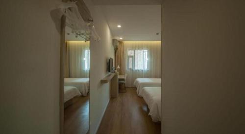 a hotel room with two beds and a mirror at 7 Days Inn Suzhou Wangting Pearl Commercial Plaza in Suzhou