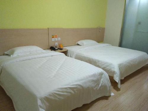 two beds in a hotel room with white sheets at 7 Days Inn Suzhou Wangting Pearl Commercial Plaza in Suzhou