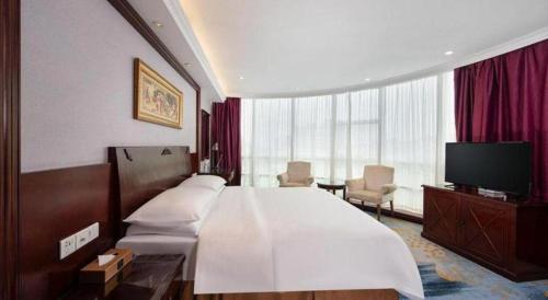 a hotel room with a large bed and a television at Vienna 3 Best Hotel Dongguan Fenggang Yongsheng Street in Tiantangwei