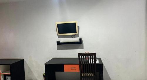 a tv sitting on a wall next to a chair at Hotel O Tri Homestay in Palangkaraya