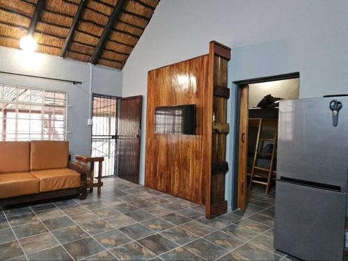 Una sala de estar con un sofá y un refrigerador. en Papagaai 2409, en Marloth Park