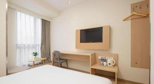 a hotel room with a bed and a desk with a television at 7 Days Inn Suzhou Mudu Ancient Town Kaima Auto Market in Suzhou
