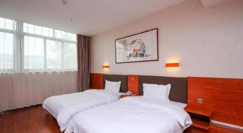 une chambre d'hôtel avec deux lits avec des draps blancs dans l'établissement 7 Days Premium·Guanyun Nanjing West Road Hesheng Plaza, à Guanyun