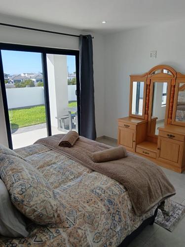 a bedroom with a bed and a large window at Kwagga Inn in Stompneusbaai