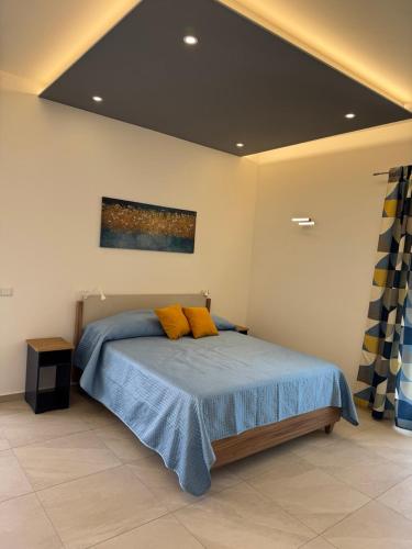 a bedroom with a bed with blue sheets and yellow pillows at Casa MaLù in Aci Bonaccorsi