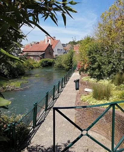 a walkway next to a river with a fence at Le Tiot Saint Martin in Auxi-le-Château