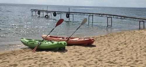 two kayaks and paddles on a beach next to the water at Norman Carr Cottage in Monkey Bay