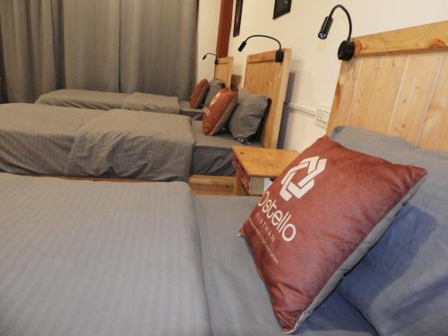 a room with three beds and a pillow at Ostello Tirthan in Bandal