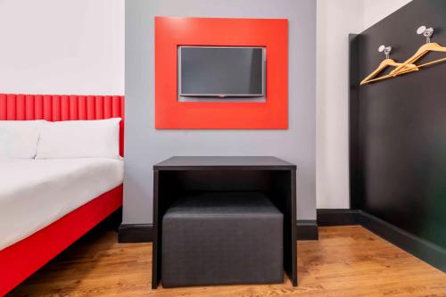 a bedroom with a bed and a tv on a wall at easyHotel Newcastle in Newcastle upon Tyne