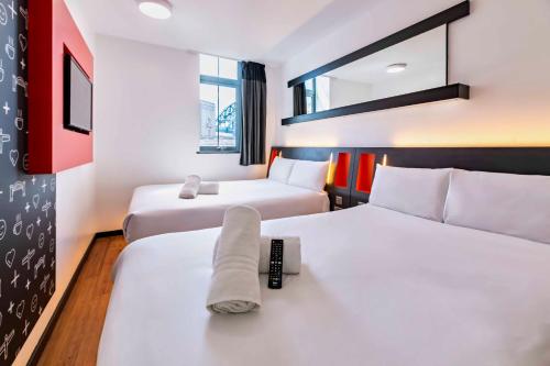 a hotel room with two beds and a remote control at easyHotel Newcastle in Newcastle upon Tyne