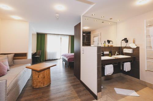 a bathroom with a sink and a bed in a room at Hotel DIE SONNE in Saalbach Hinterglemm