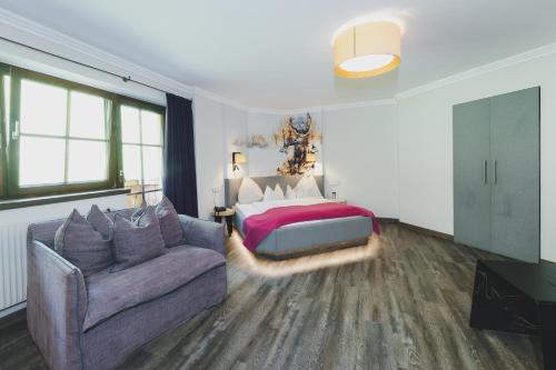 a bedroom with a bed and a couch at Hotel DIE SONNE in Saalbach Hinterglemm