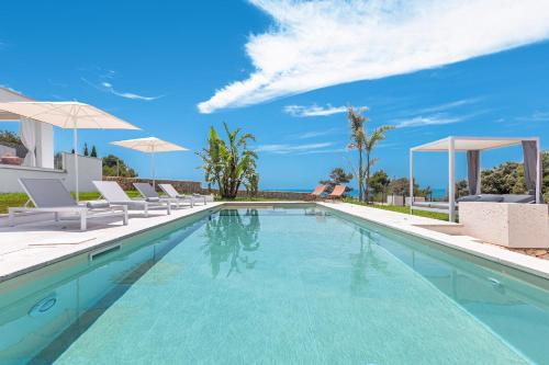 a swimming pool with chairs and umbrellas in a villa at Villa Demetra by SalentoInVacanzaCOM in Marina di Pescoluse