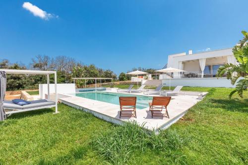 a swimming pool with chairs and a house at Villa Demetra by SalentoInVacanzaCOM in Marina di Pescoluse
