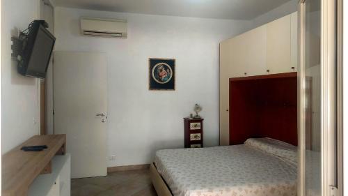 Un dormitorio con una cama y un televisor de pantalla plana. en Costa Degli Eucalipti, en Gaeta