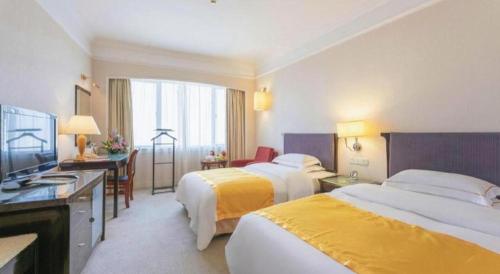a hotel room with two beds and a television at Shantou Golden Gulf Hotel in Shantou
