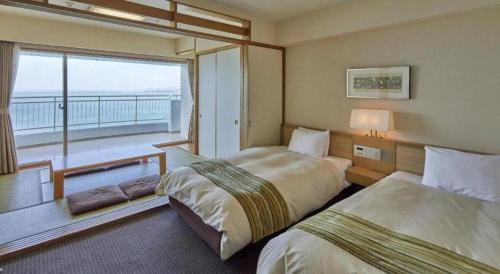 a hotel room with two beds and a balcony at Hotel Harvest Nankitanabe in Tanabe