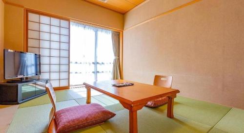 a living room with a table and a tv at Ooedo Onsen Monogatari Minoh Kanko Hotel in Minoo