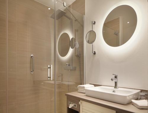 a bathroom with a sink and a shower with a mirror at Hotel Inselfriede in Spiekeroog