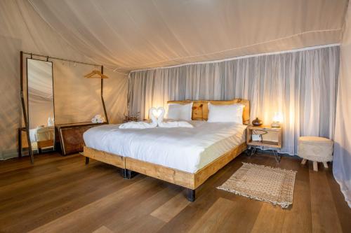 a bedroom with a large bed in a tent at Rom Farm by Glow - חוות רום in Kammon