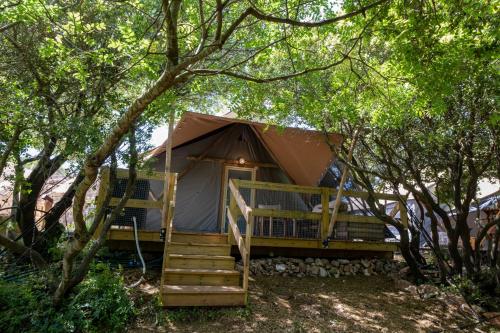 a tent in the woods with a porch and stairs at Rom Farm by Glow - חוות רום in Kammon