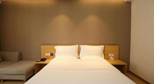 a bedroom with a white bed and a couch at 7 Days Premium Chongqing Longtou Temple North Railway Station Center in Chongqing