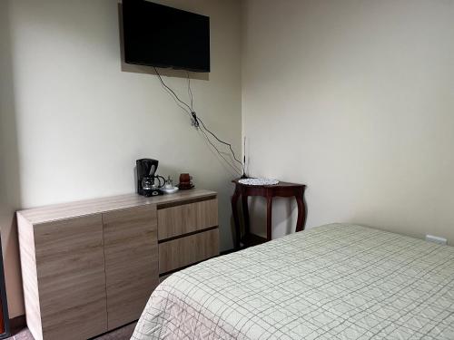 a bedroom with a bed and a tv on the wall at Alojamiento Privado in Otavalo