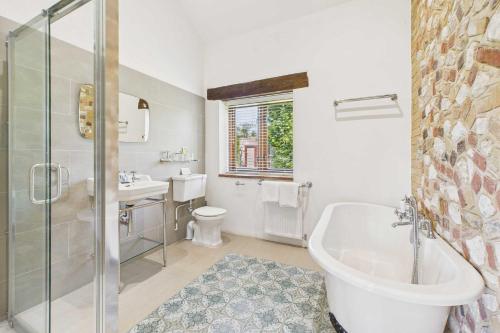 a bathroom with a tub and a toilet and a sink at Host & Stay - The Old Foundry in Beechamwell