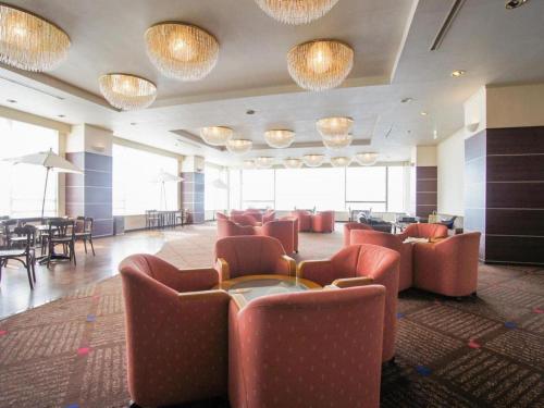 a hotel lobby with red chairs and tables and chandeliers at Hotel AreaOne Banjinmisaki in Kashiwazaki