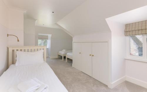 a white bedroom with a bed and a window at NEW JULY 2025 - Grand Clifftop Duplex with Panoramic Views, Games Room & Stylish Interiors in Shanklin Old Village in Shanklin