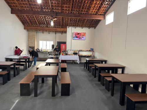 a room with tables and benches and people in the background at HOTEL Pousada ACONCHEGO Promissão in Promissão