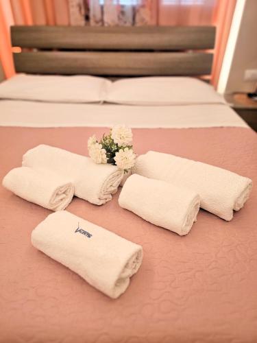 four white towels and flowers on a bed at Affittacamere Casa Brajan in Follonica