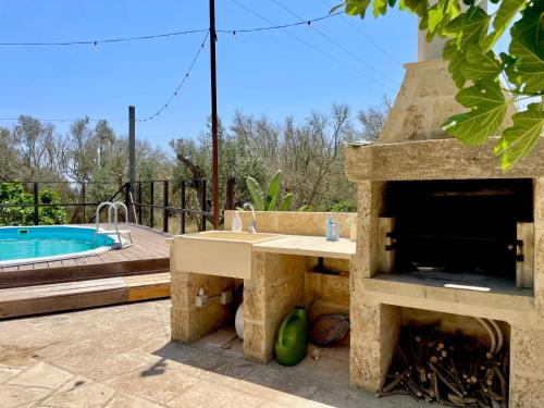 a stone outdoor kitchen with a fireplace next to a swimming pool at Villa Eos con Piscina Privata nel cuore del Parco Naturale di Andrano in Andrano