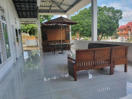 a porch with a bench and a table and an umbrella at Hotel O Losmen Bunda Arema in Bangko