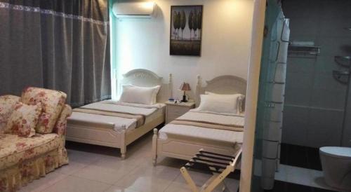 a room with two beds and a couch and a shower at Crystal Palace Hotel in Port Vila