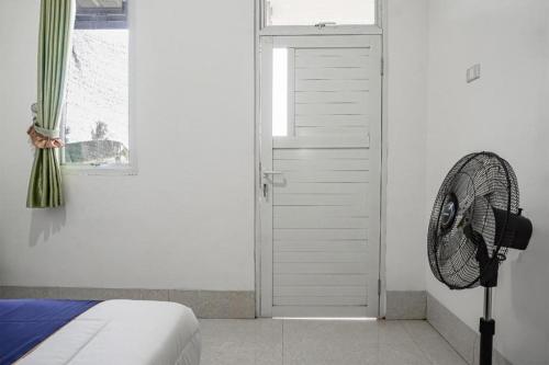 a bedroom with a fan next to a door at Hotel O Wisma Sidosari Syariah in Bandar Lampung