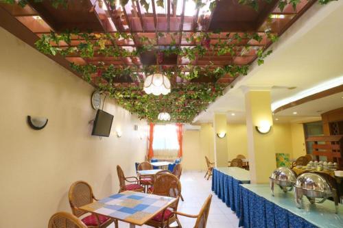 a restaurant with tables and chairs and plants on the ceiling at Hotel Permata Bandara in Jakarta