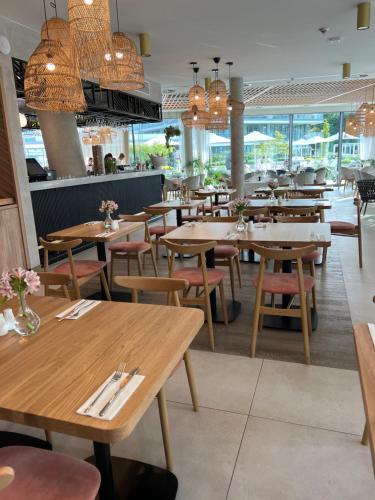 a restaurant with wooden tables and chairs and chandeliers at Waveview Premium Apartment Międzyzdroje in Międzyzdroje