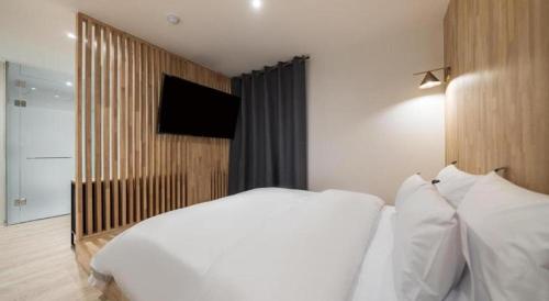 a bedroom with a white bed and a flat screen tv at Crossing Hotel in Seoul