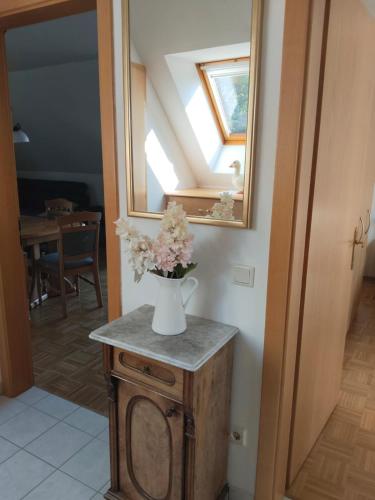 a vase of flowers on a table with a mirror at Appartement Fernblick in Kitzeck im Sausal