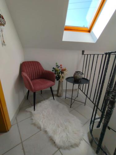 a living room with a red chair and a white rug at Appartement Fernblick in Kitzeck im Sausal