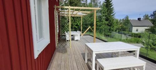 a wooden deck with two tables and a swing at Lottefors Logi in Bollnäs