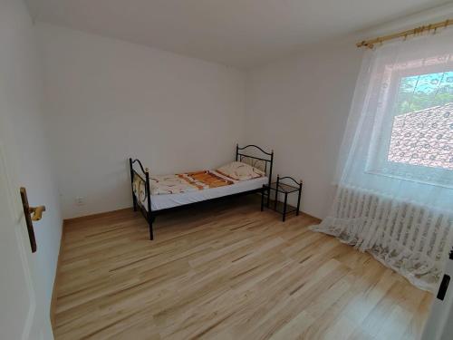 ein Schlafzimmer mit einem Bett, einem Fenster und einem Holzboden in der Unterkunft Soukromé ubytování u lesa in Ostrava