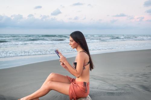 a woman sitting on the beach looking at her cell phone at Hotel Playa Palmeras Cartagena - Vía al Mar in Cartagena de Indias