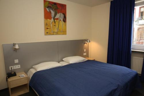 a bedroom with a bed with a blue comforter at Hotel Münchner Hof in Frankfurt