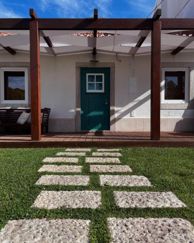 a house with a green door and a grass yard at Casa da Avó in Sesimbra