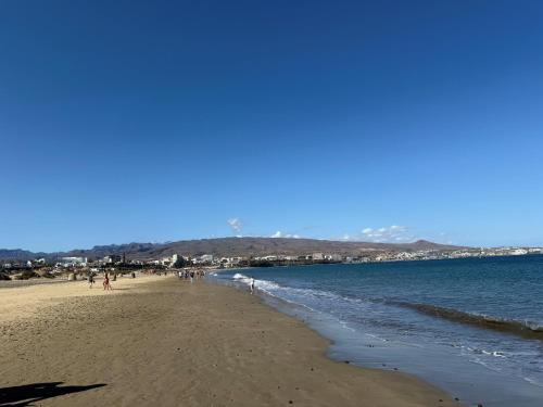 a beach with people walking on the sand and the water at 2-bedroom apartment in Playa del Inglés - El Dorado in Maspalomas
