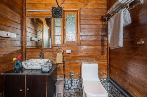 La salle de bains en bois est pourvue de toilettes et d'un lavabo. dans l'établissement Stay Leisurely Woodscape 5BHK, Pawna Lake, à Malavli