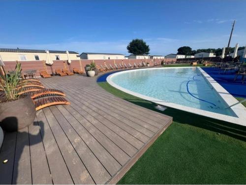 a swimming pool with chairs and a wooden deck at Spacious 6 Bed Caravan with Decking in Hayling Island